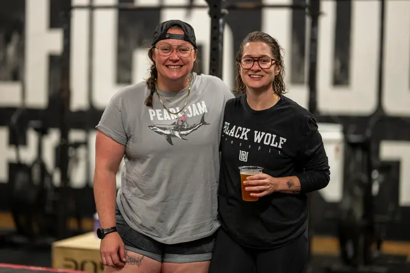 Two members posing in front of the Black Wolf wall